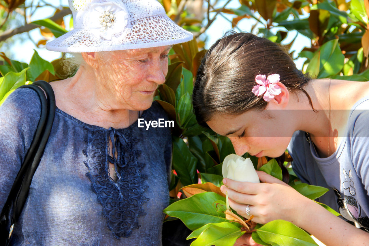 Young woman smelling white magnolia by grandmother