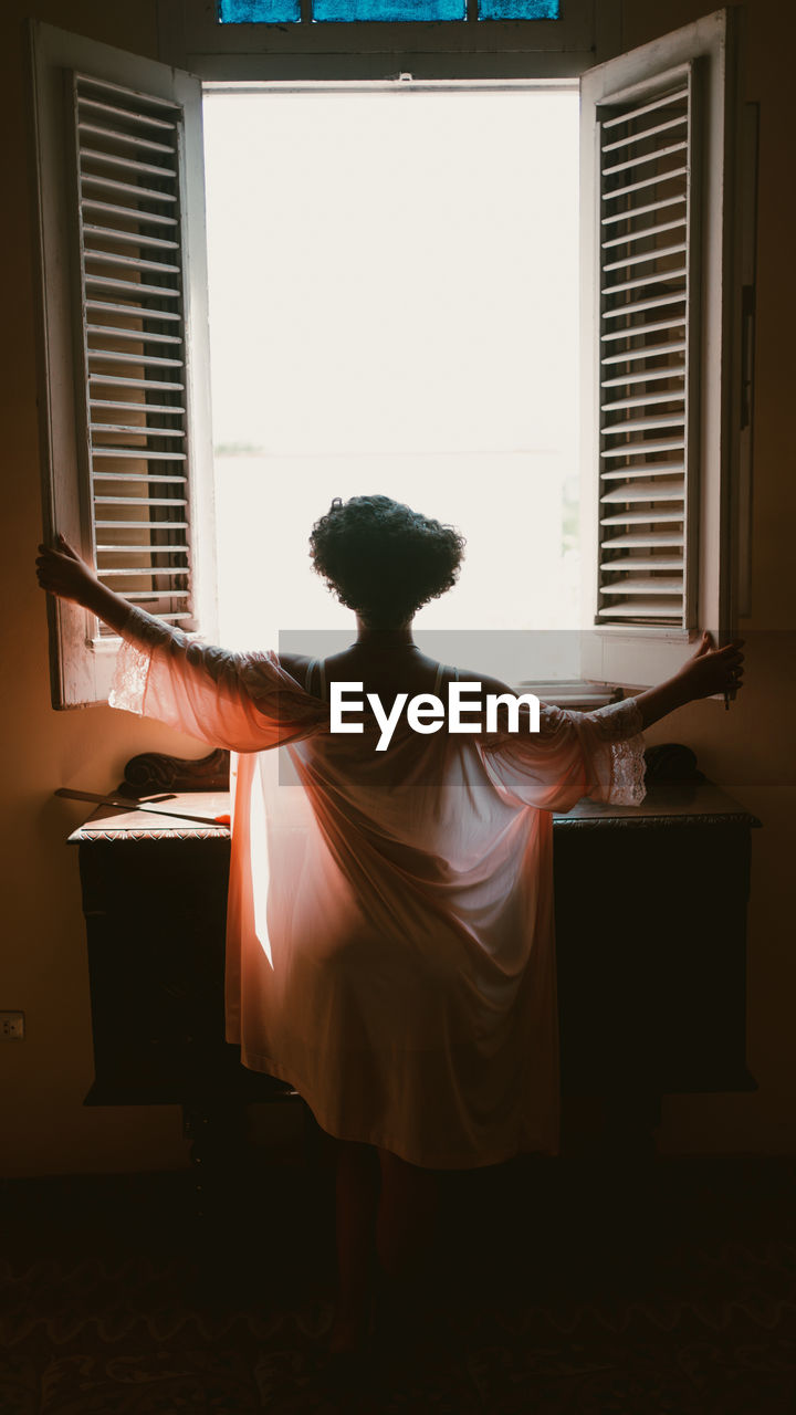 Side view of woman looking away while standing at home