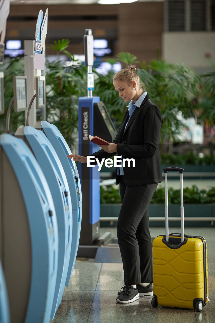 FULL LENGTH OF MAN HOLDING CAMERA WHILE STANDING AT THE PHONE