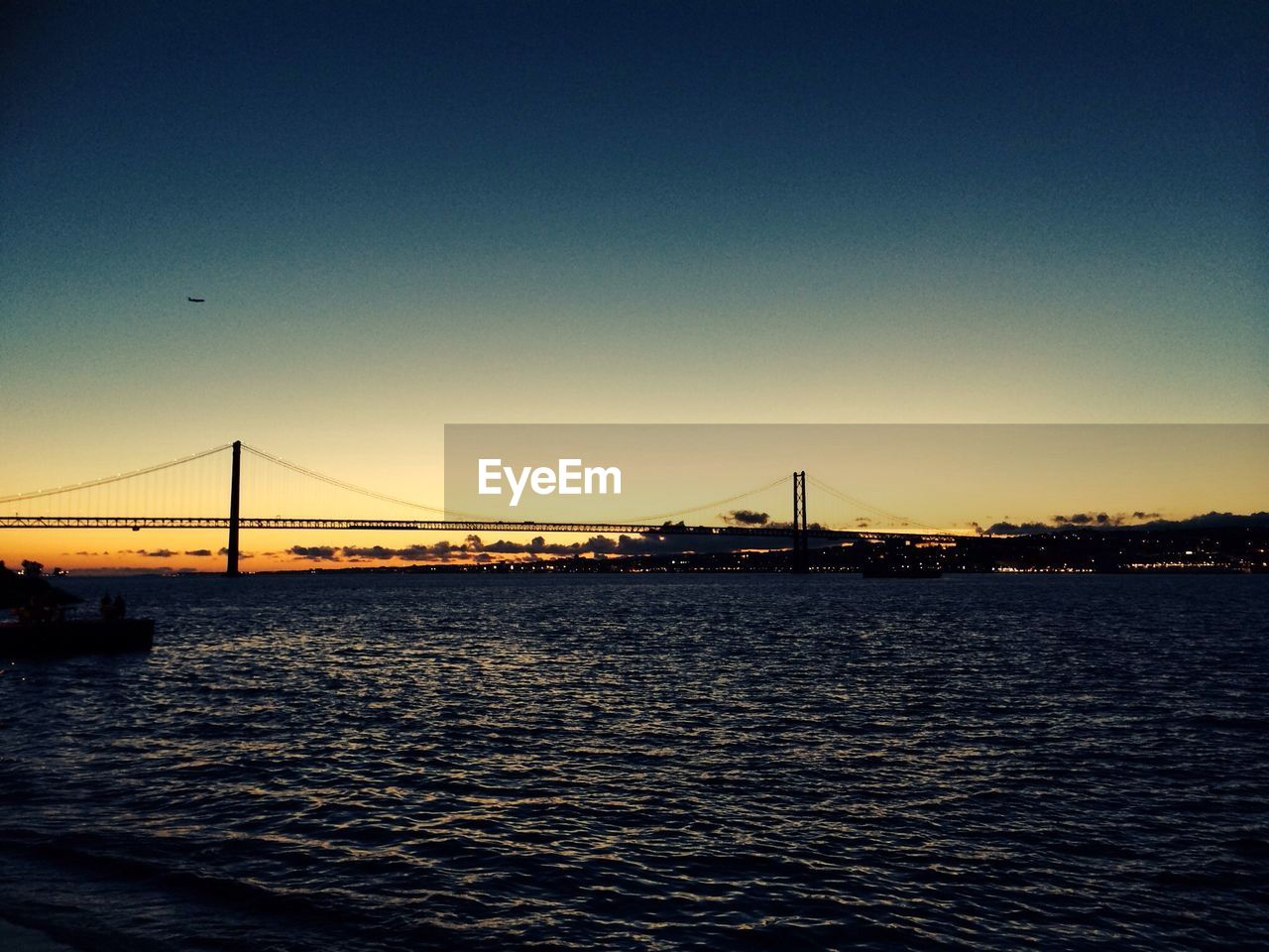 Scenic view of sea with suspension bridge during sunset