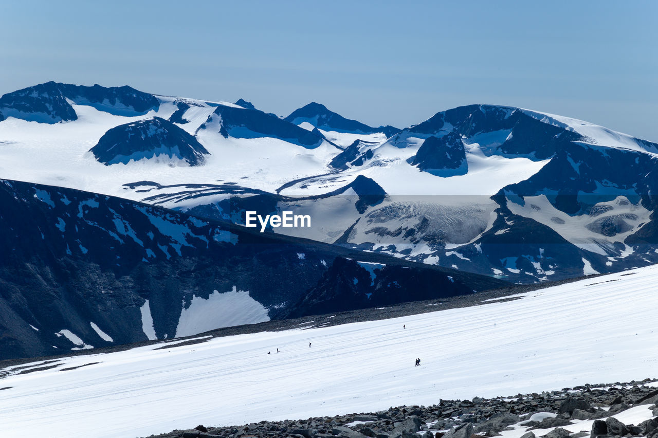 People descending glittertind in jotunheimen, norway. midsummer.