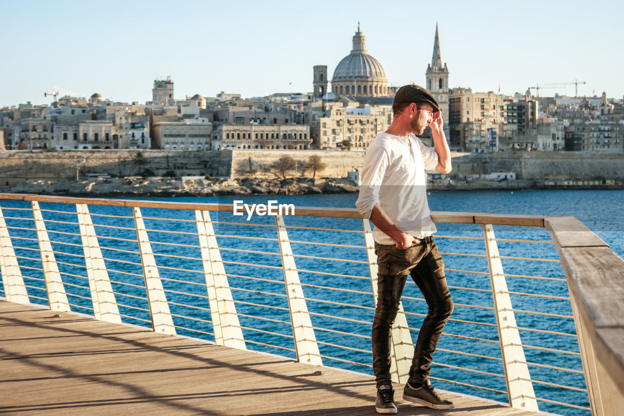 Full length of man standing on railing on footbridge over river