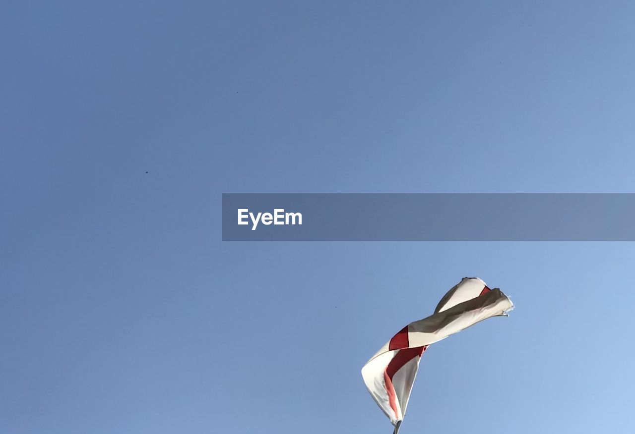 sky, blue, flying, windsports, toy, copy space, sports, clear sky, nature, no people, wind, low angle view, day, kite - toy, sunny, animal, mid-air, outdoors, flag, animal themes, environment, kite sports, bird, kite, wing, motion