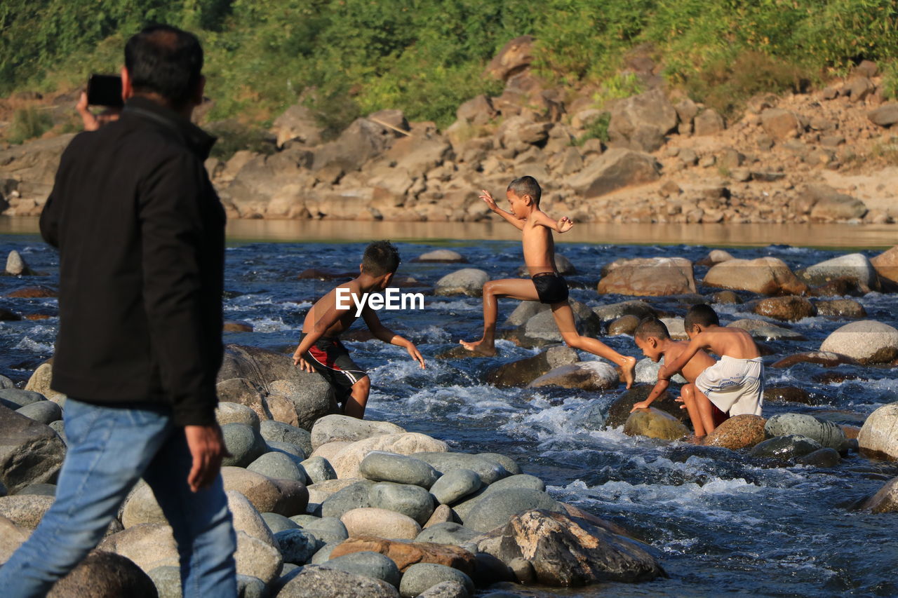 Shirtless boys playing in river