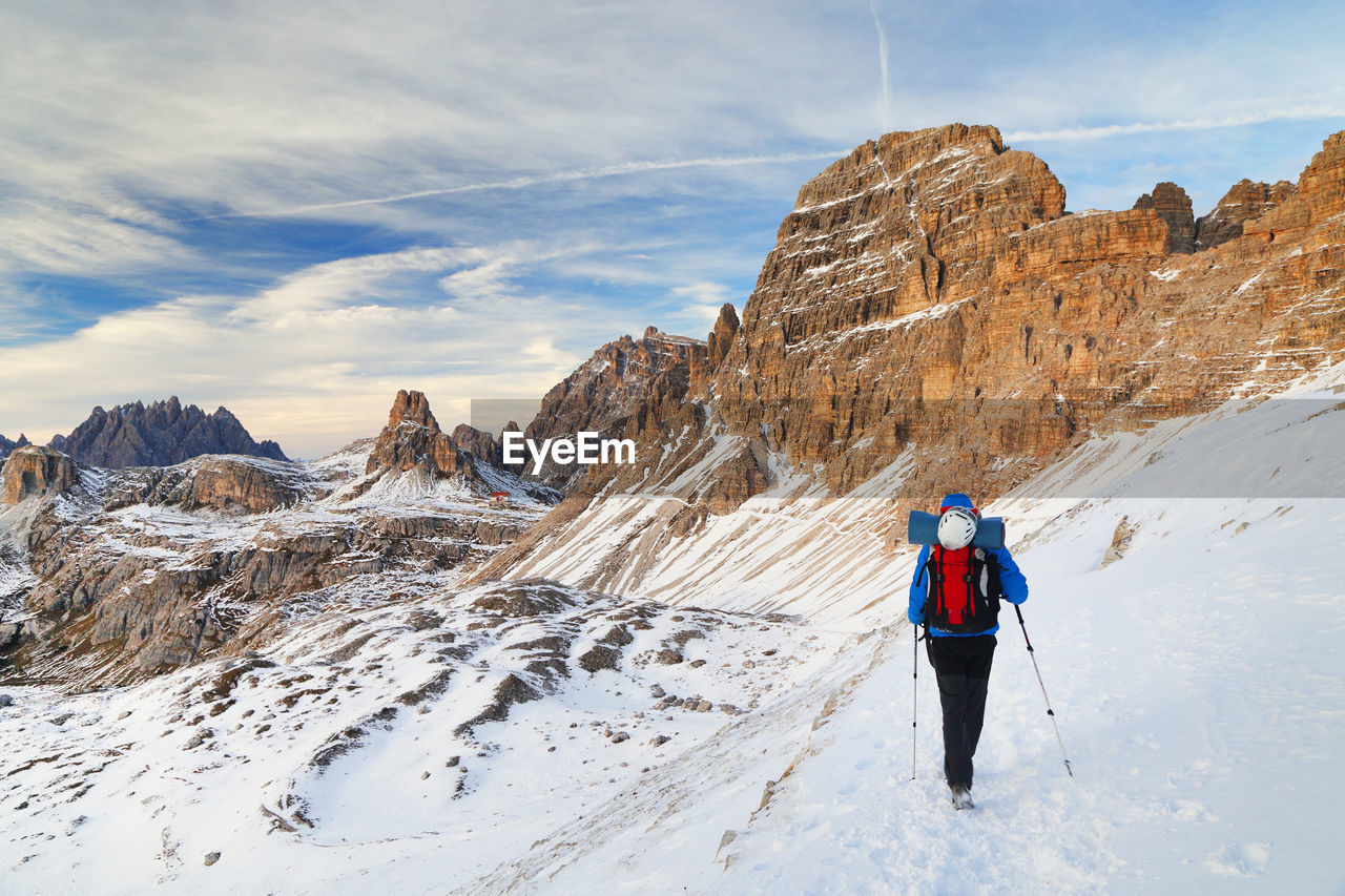 Rear view of woman standing on snowcapped mountain against sky