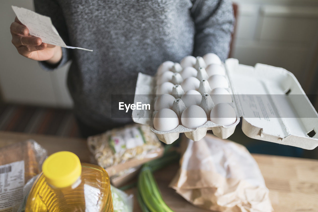 Woman checking receipt from supermarket during inflation with rise in price of food and consumer products