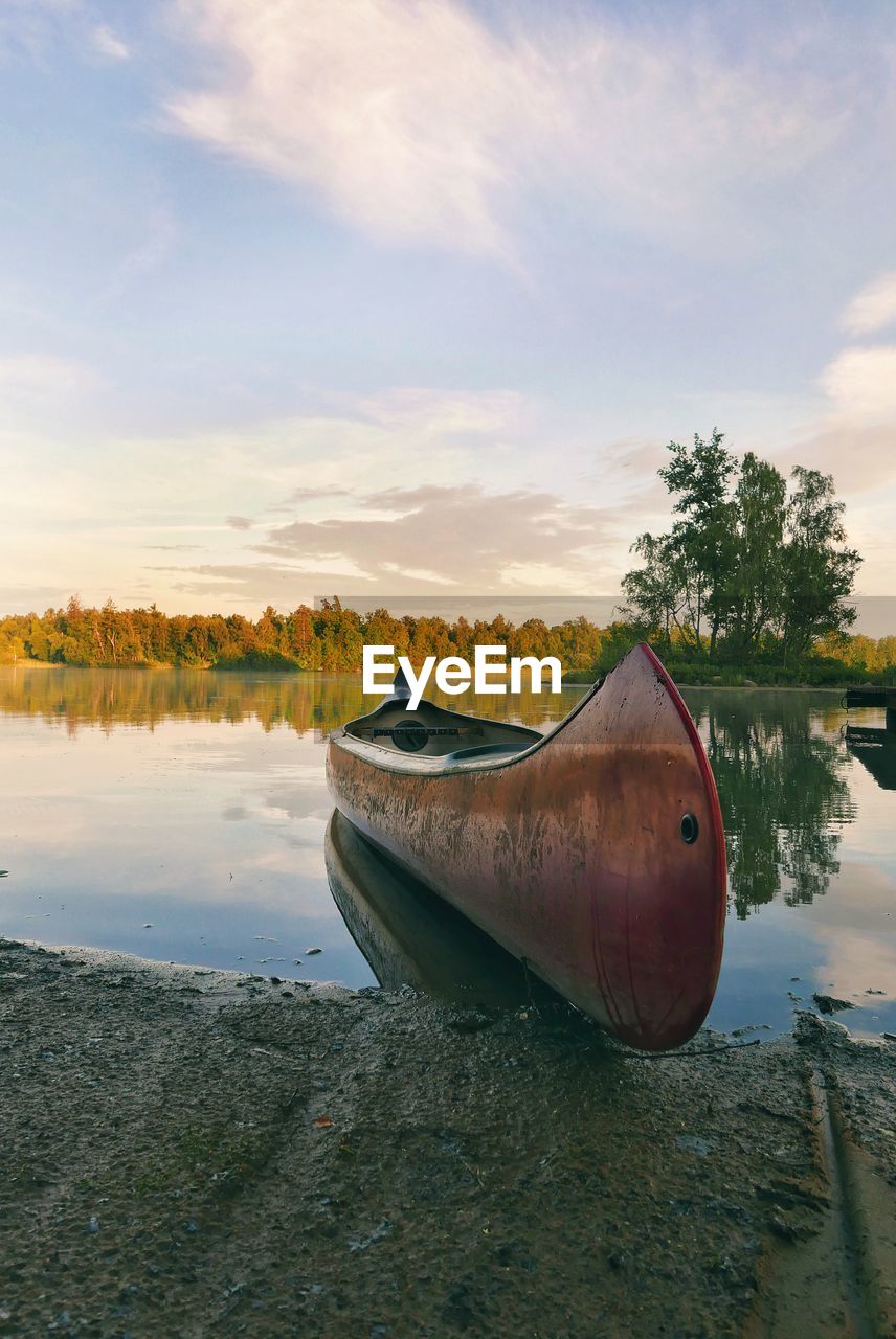 BOAT MOORED ON LAKE AGAINST SKY