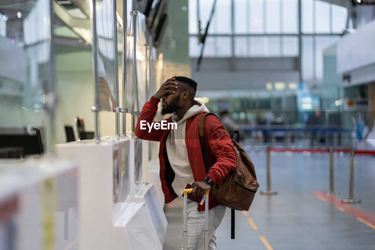 Upset african student guy in airport feeling uncertain about moving to another country