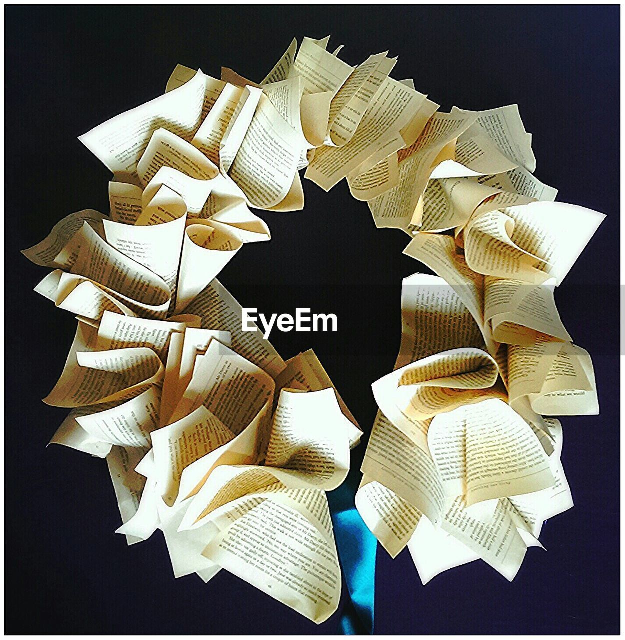 Circle made from folded papers against black background