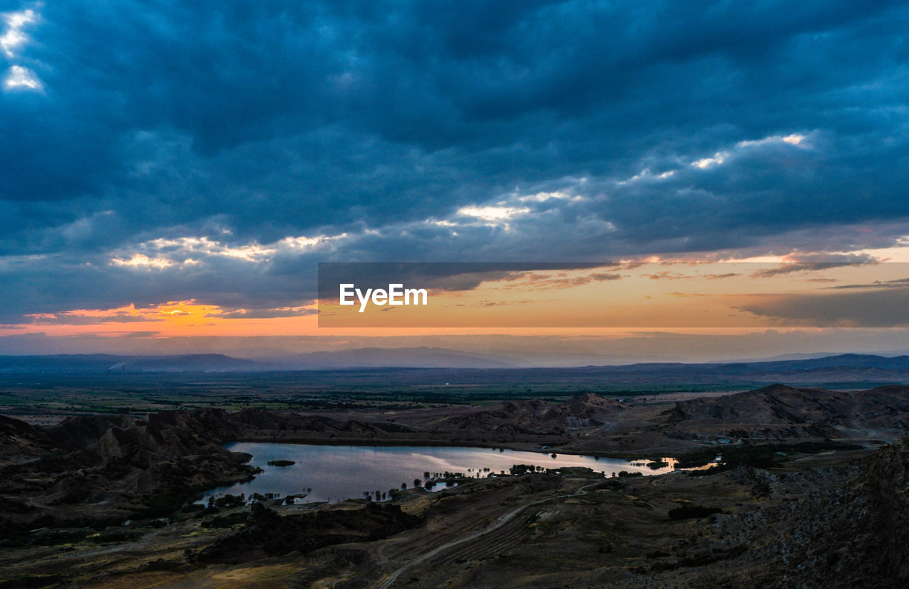 Scenic view of landscape against dramatic sky during sunset