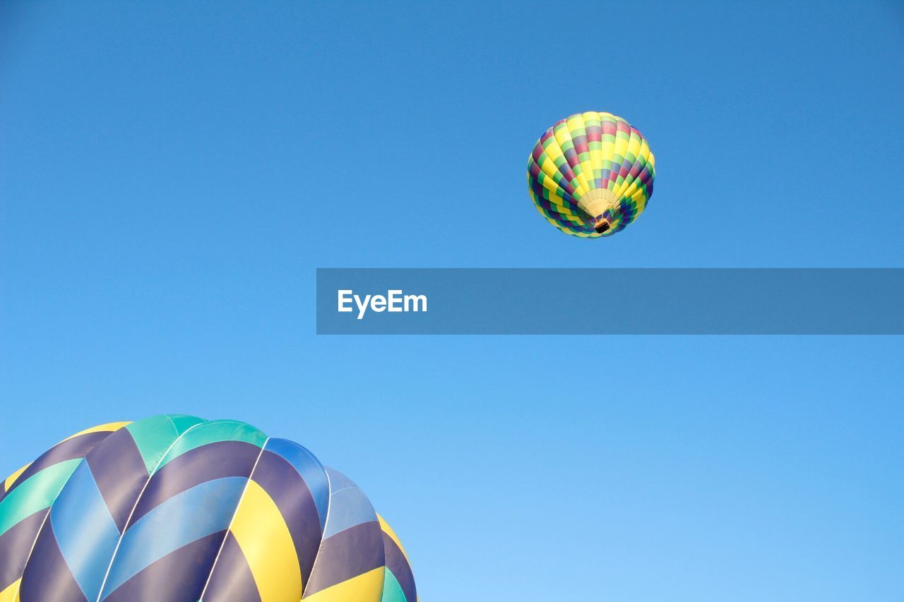 Low angle view of colorful hot air balloons flying in clear blue sky