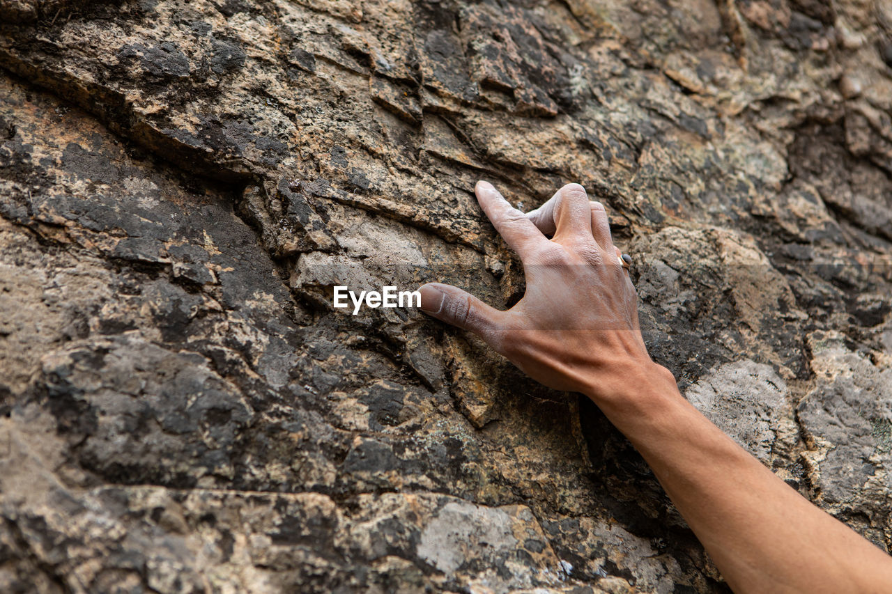 Midsection of human hand on rock