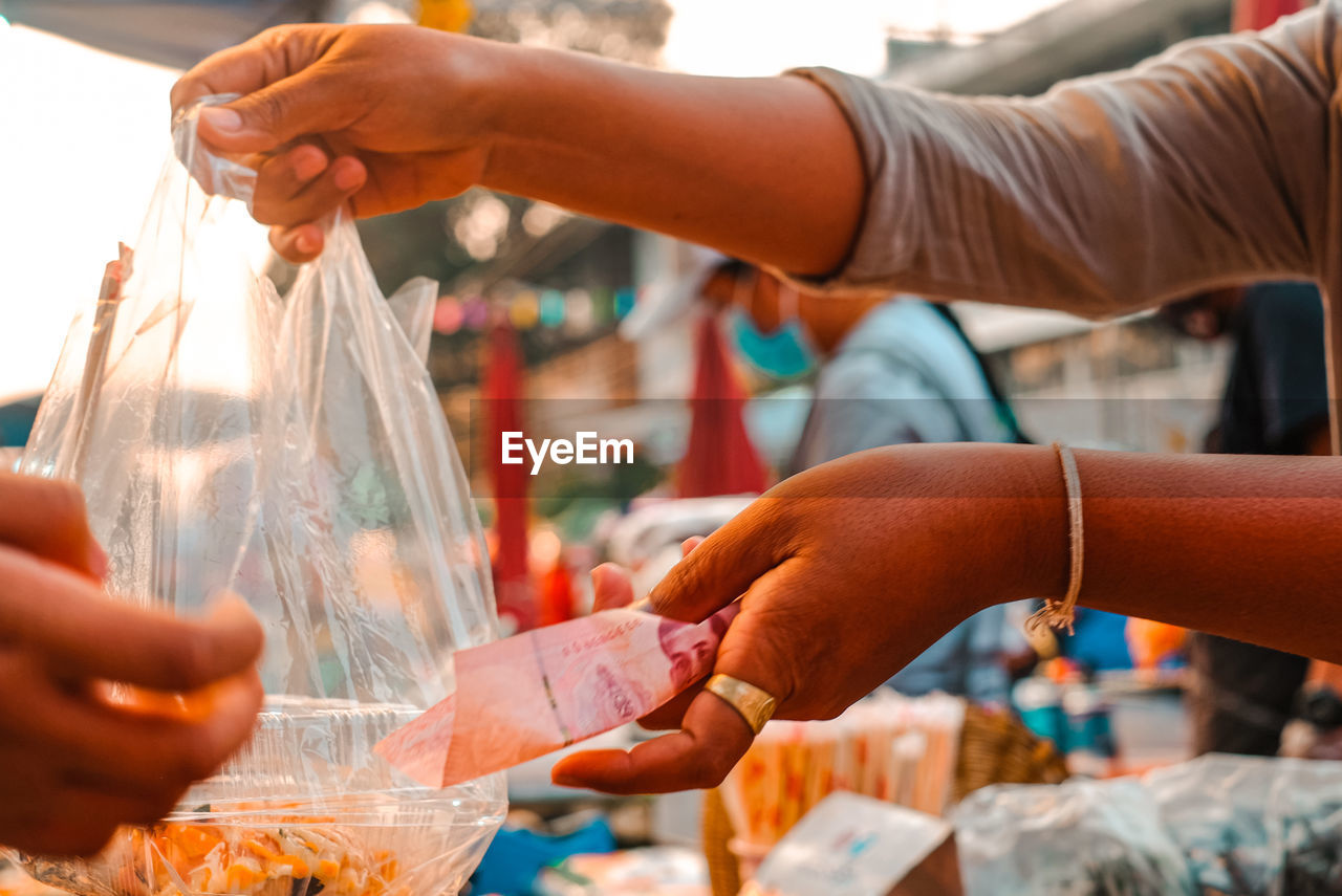 Midsection of people holding ice cream in market