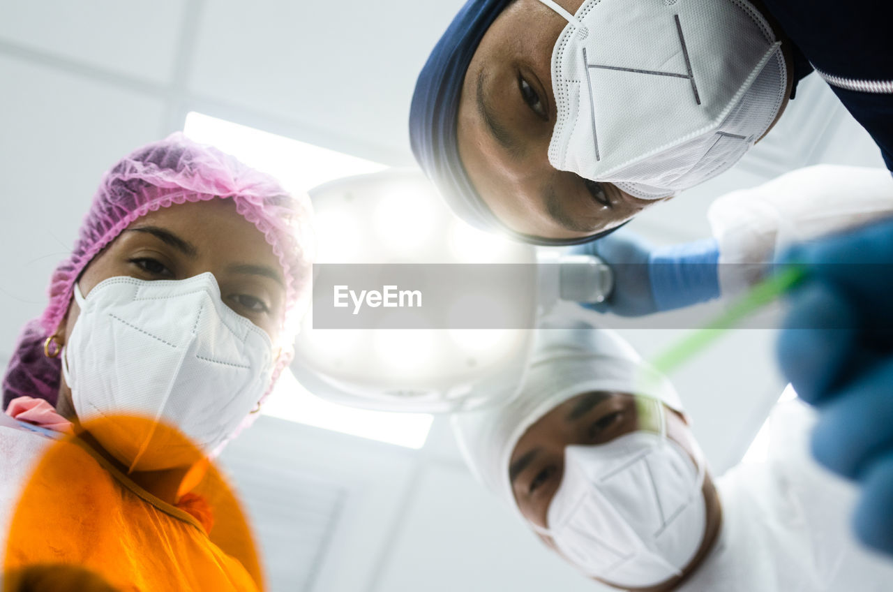 Low angle view of surgeons wearing mask in operating theater