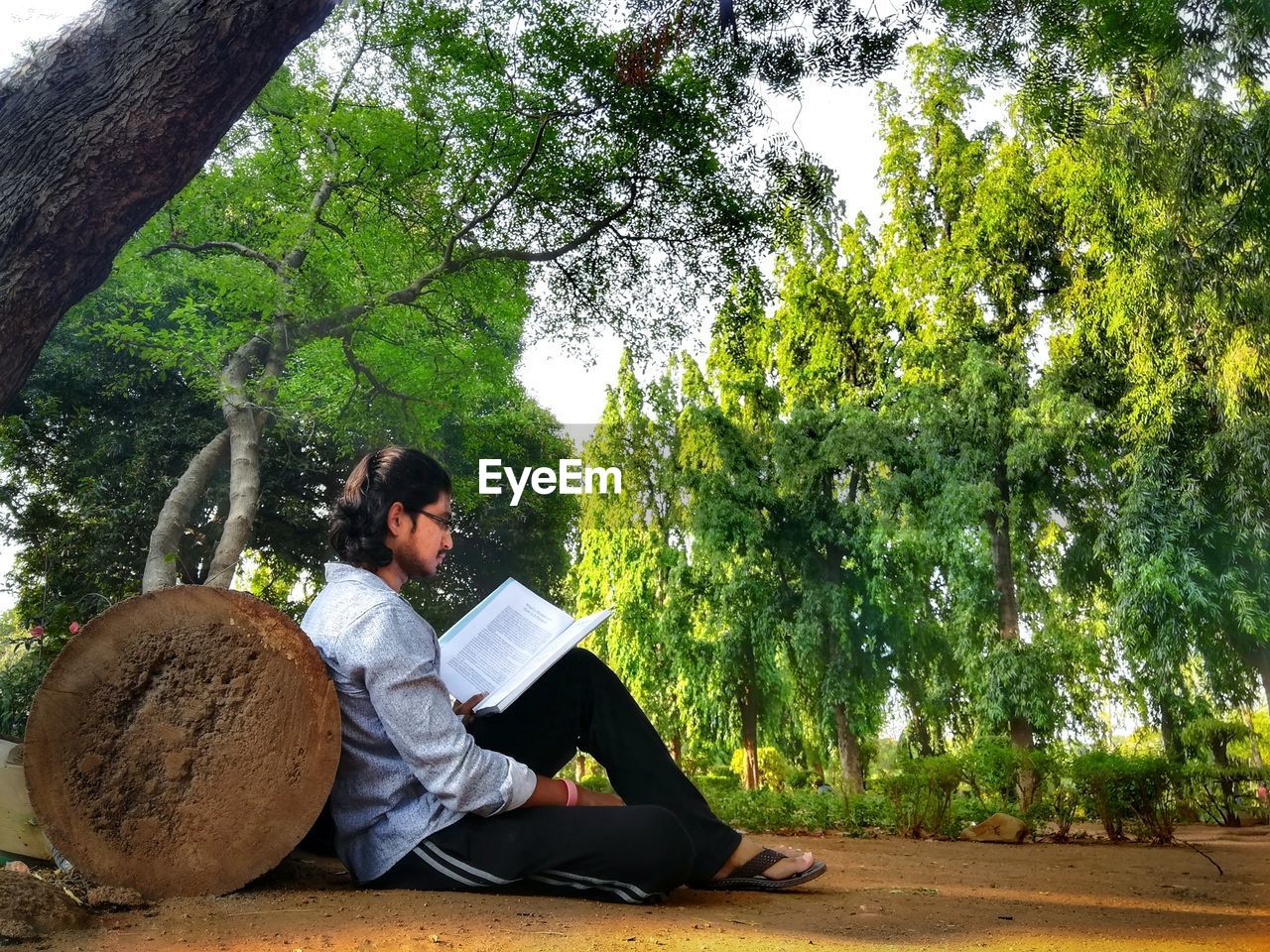 Side view of man reading book while sitting on field