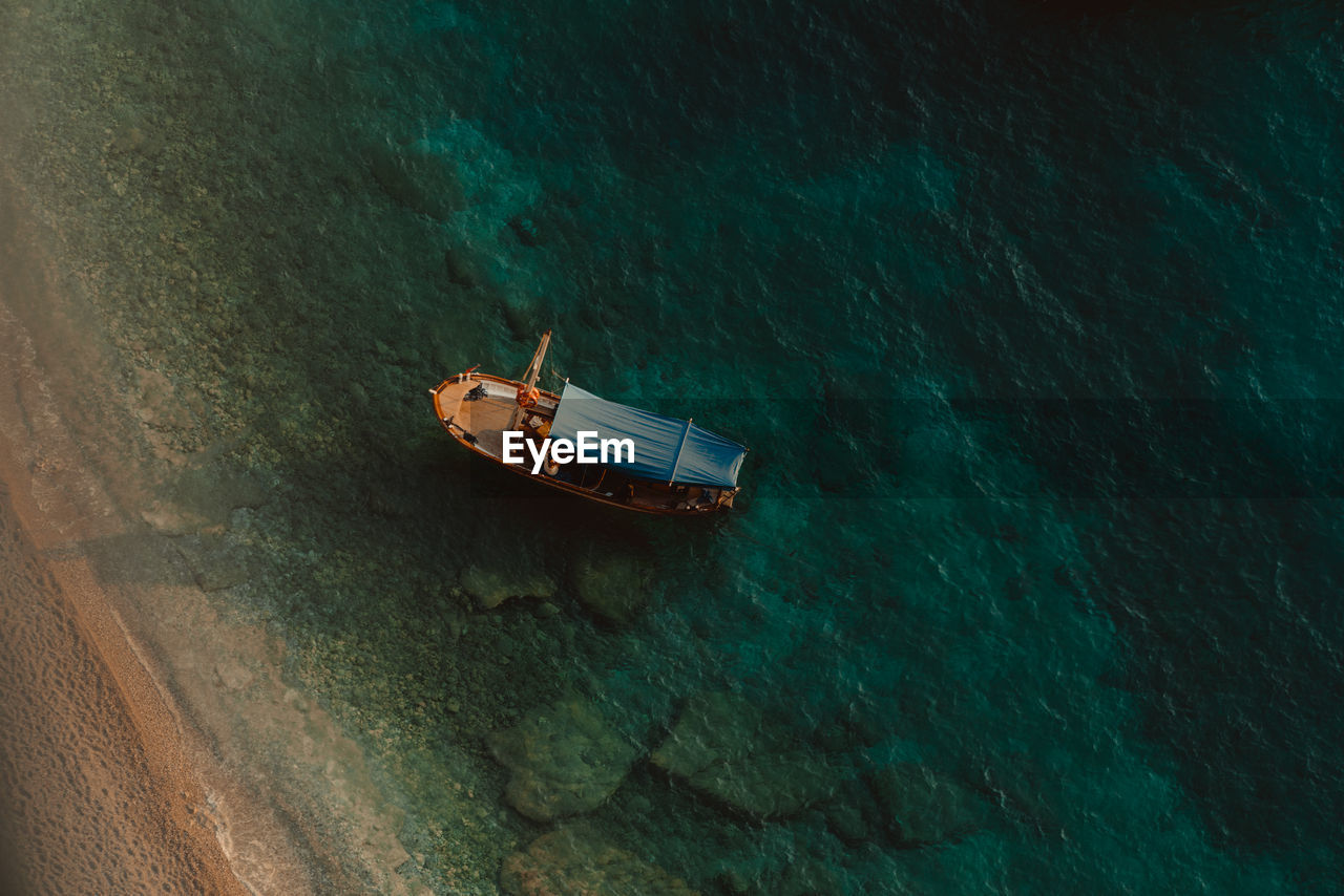 HIGH ANGLE VIEW OF SAILBOAT SAILING IN SEA