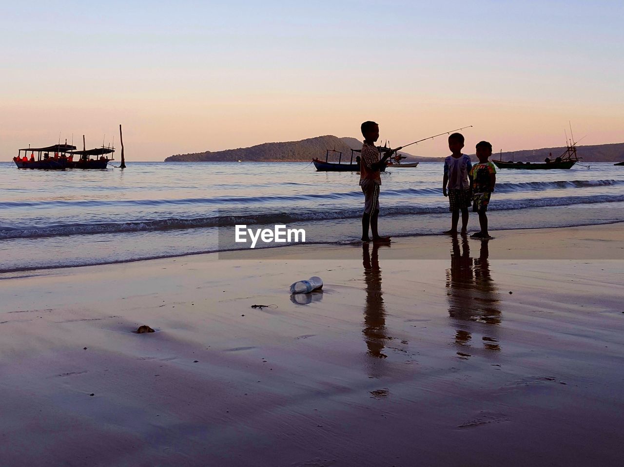 PEOPLE FISHING ON BEACH AGAINST CLEAR SKY