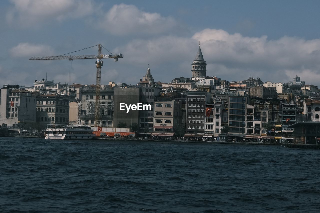 Sea by buildings against sky in city