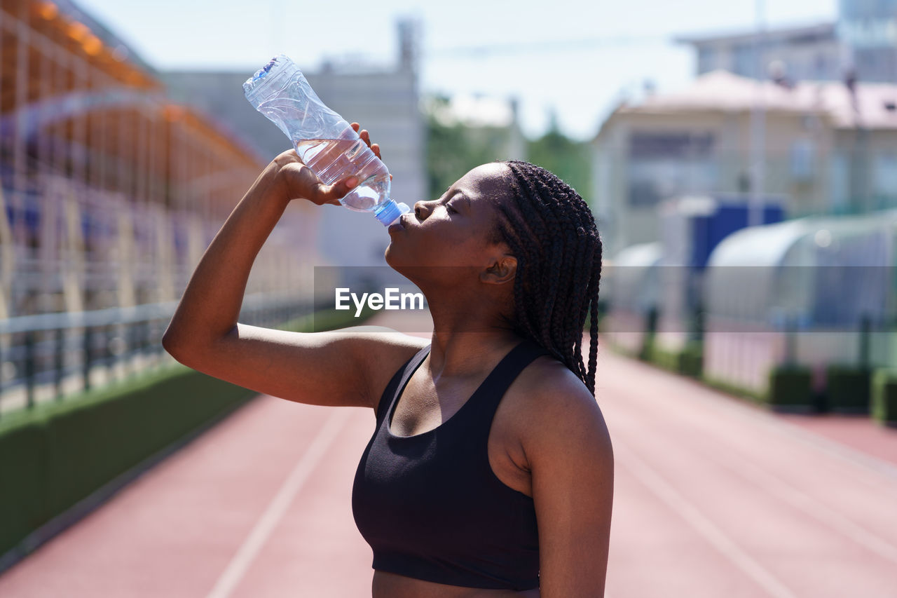 Athletic african american woman athlete drinks water after long run to replenish fluid in blood