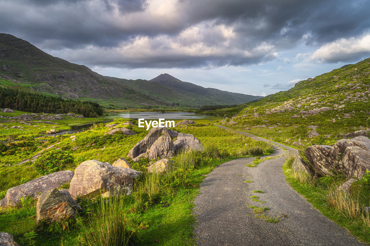 Beautiful landscape with winding country road illuminated by sunlight at sunset black valley ireland