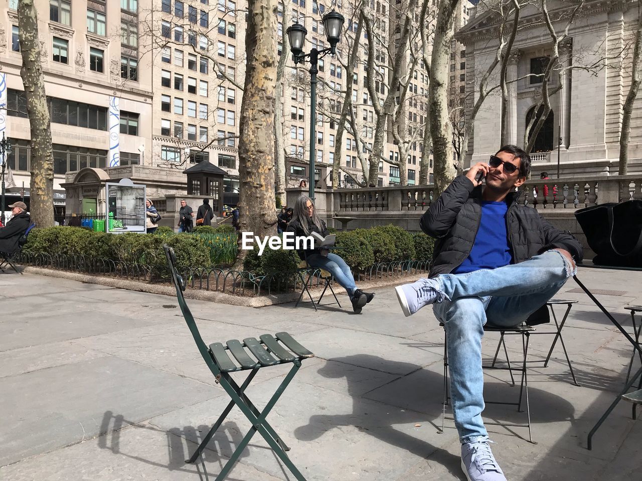 Man talking on phone while sitting on chair in city