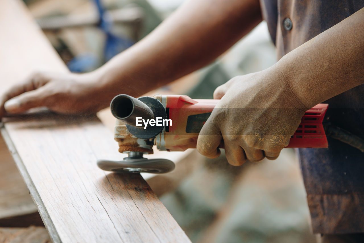 Midsection of man working on wood at workshop