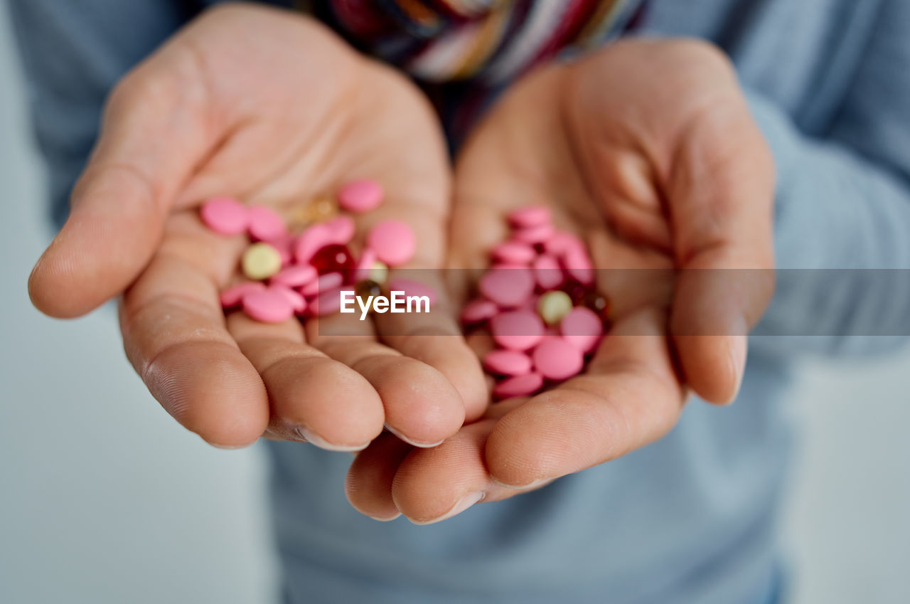 CLOSE-UP OF HAND HOLDING PINK FLOWERS