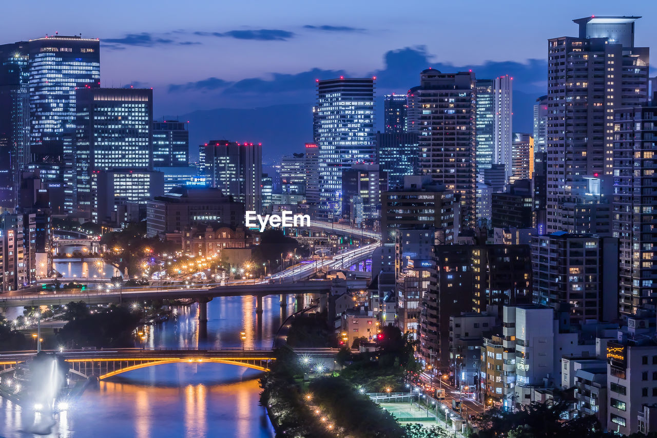 Illuminated buildings and bridge in city