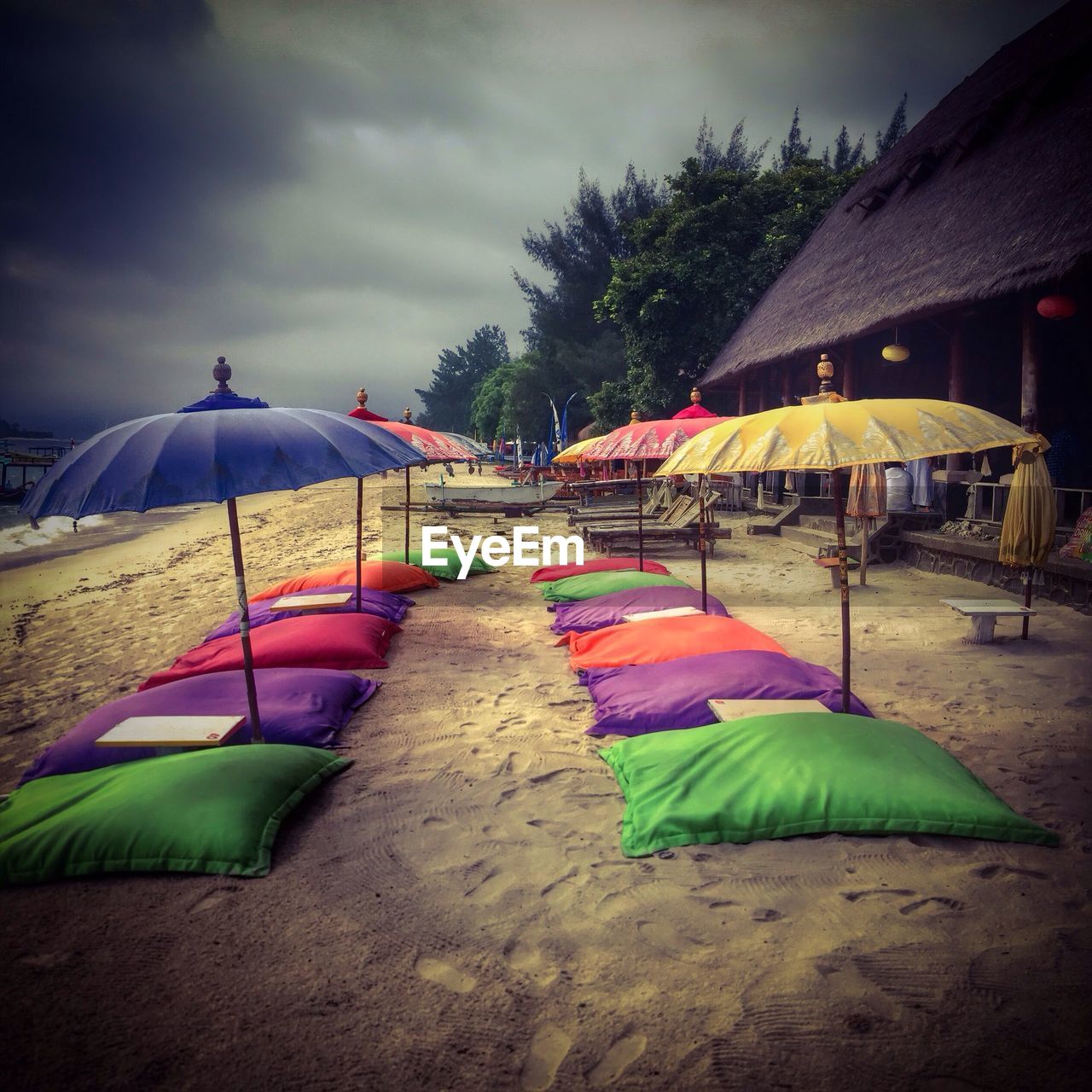 Parasols and pillows at beach against sky