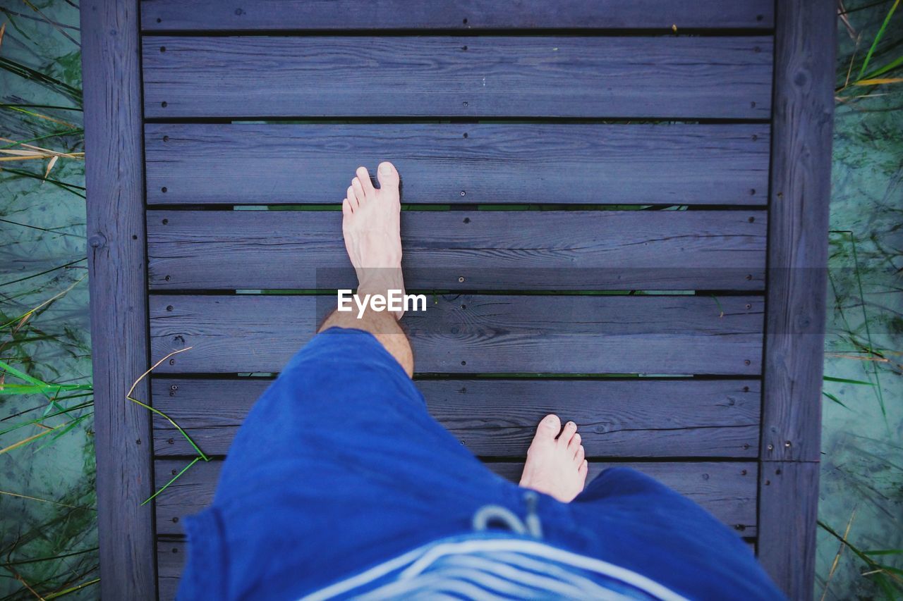 Low section of man on wooden pier over lake