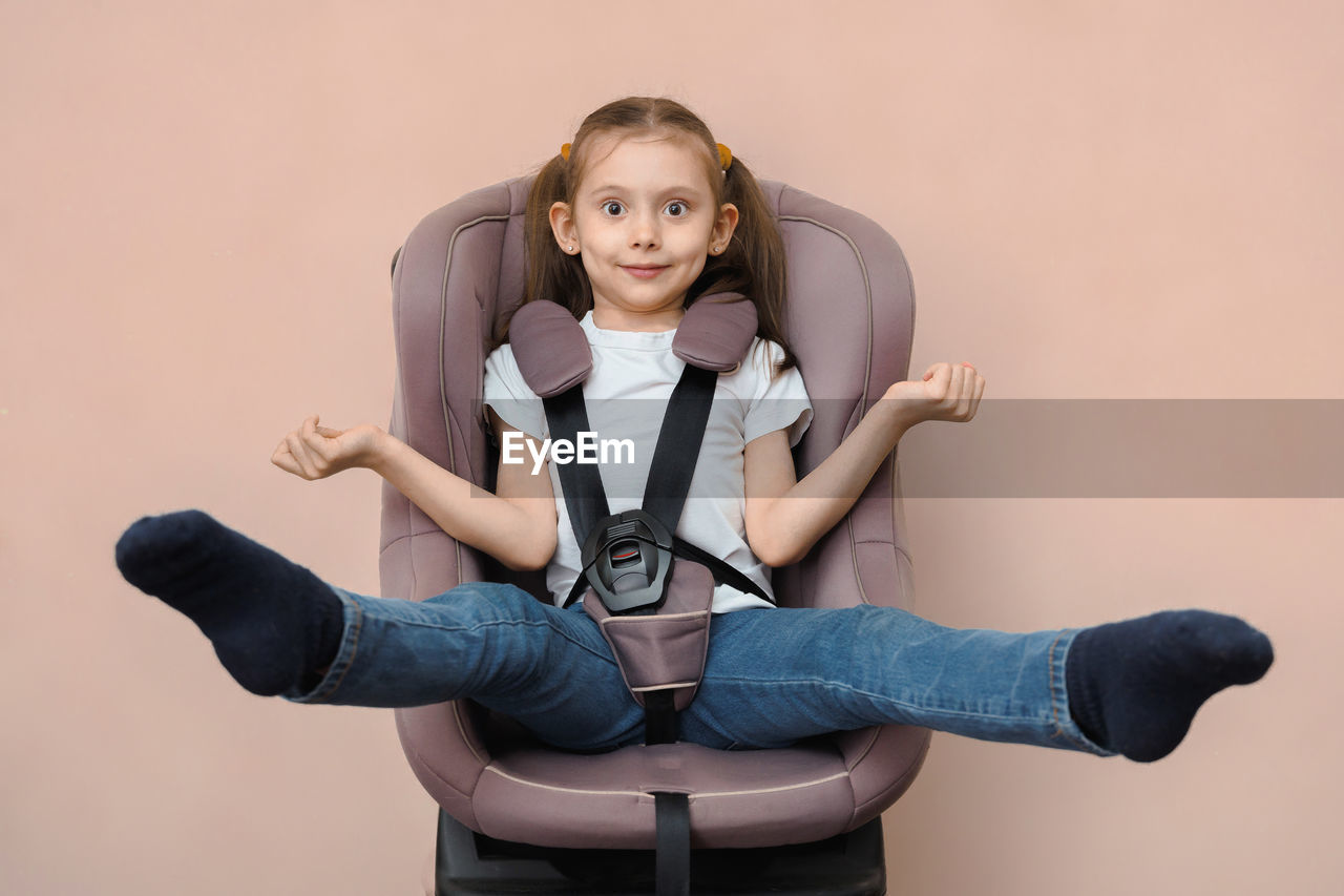 sitting, one person, portrait, women, looking at camera, studio shot, indoors, adult, front view, smiling, child, lifestyles, clothing, emotion, childhood, female, person, happiness, colored background, young adult, human leg, photo shoot, copy space, limb, casual clothing, full length, fun, relaxation