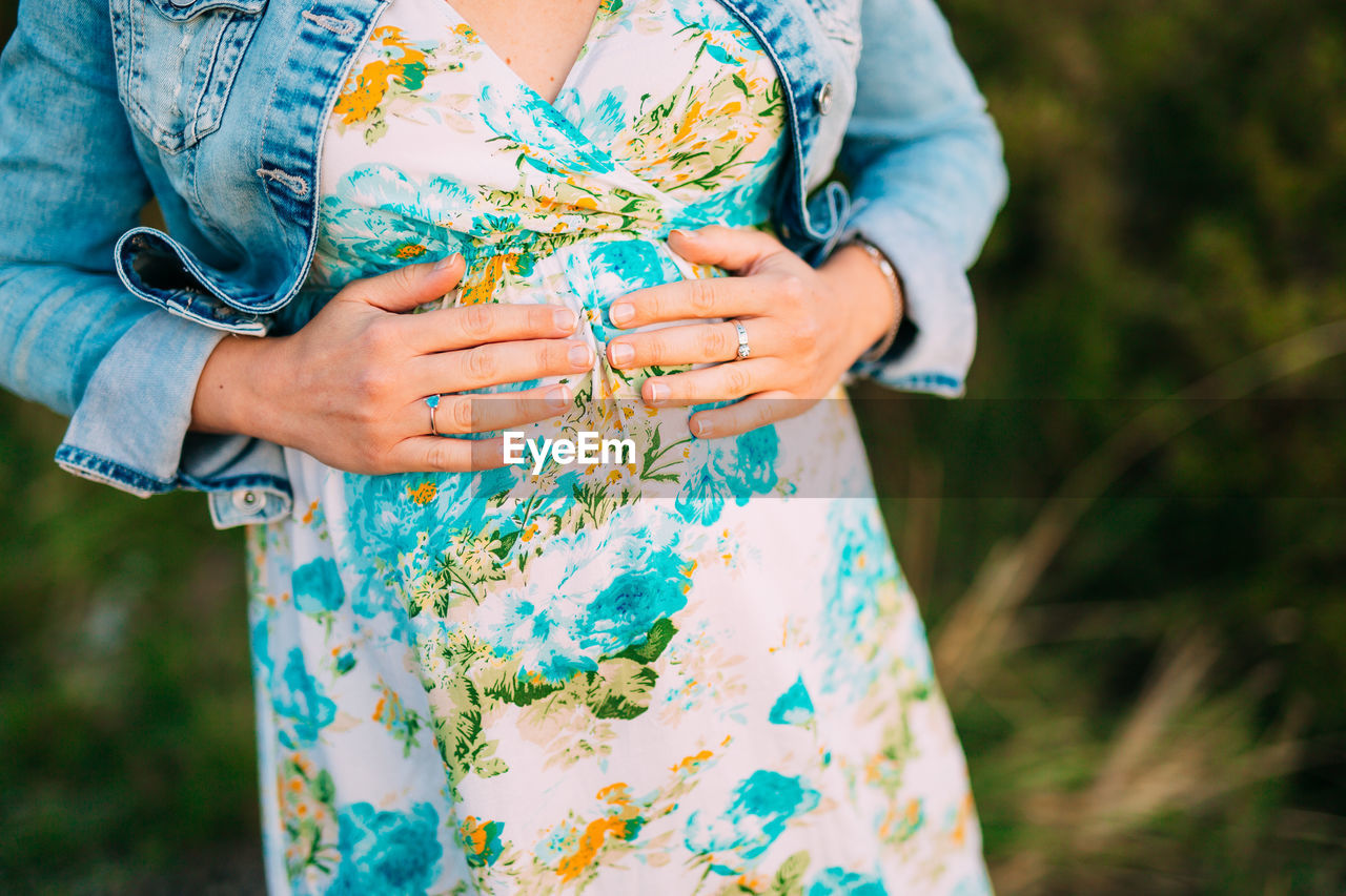 Midsection of pregnant woman standing outdoors