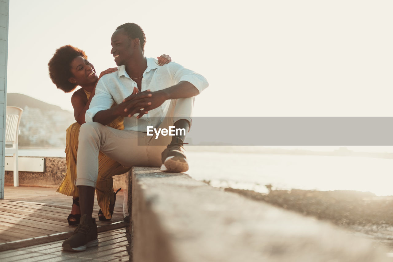 side view of couple sitting on retaining wall