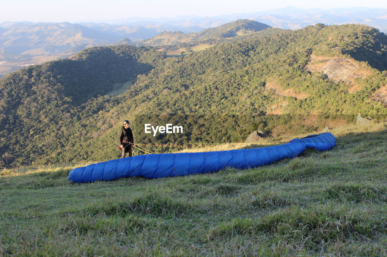 High angle view of man paragliding on grassy mountain