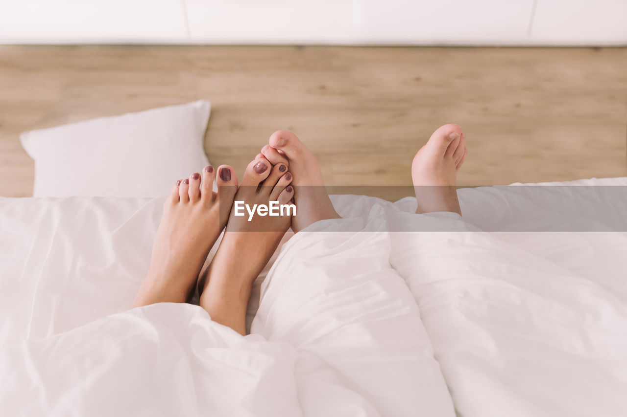 Low section of woman lying on bed