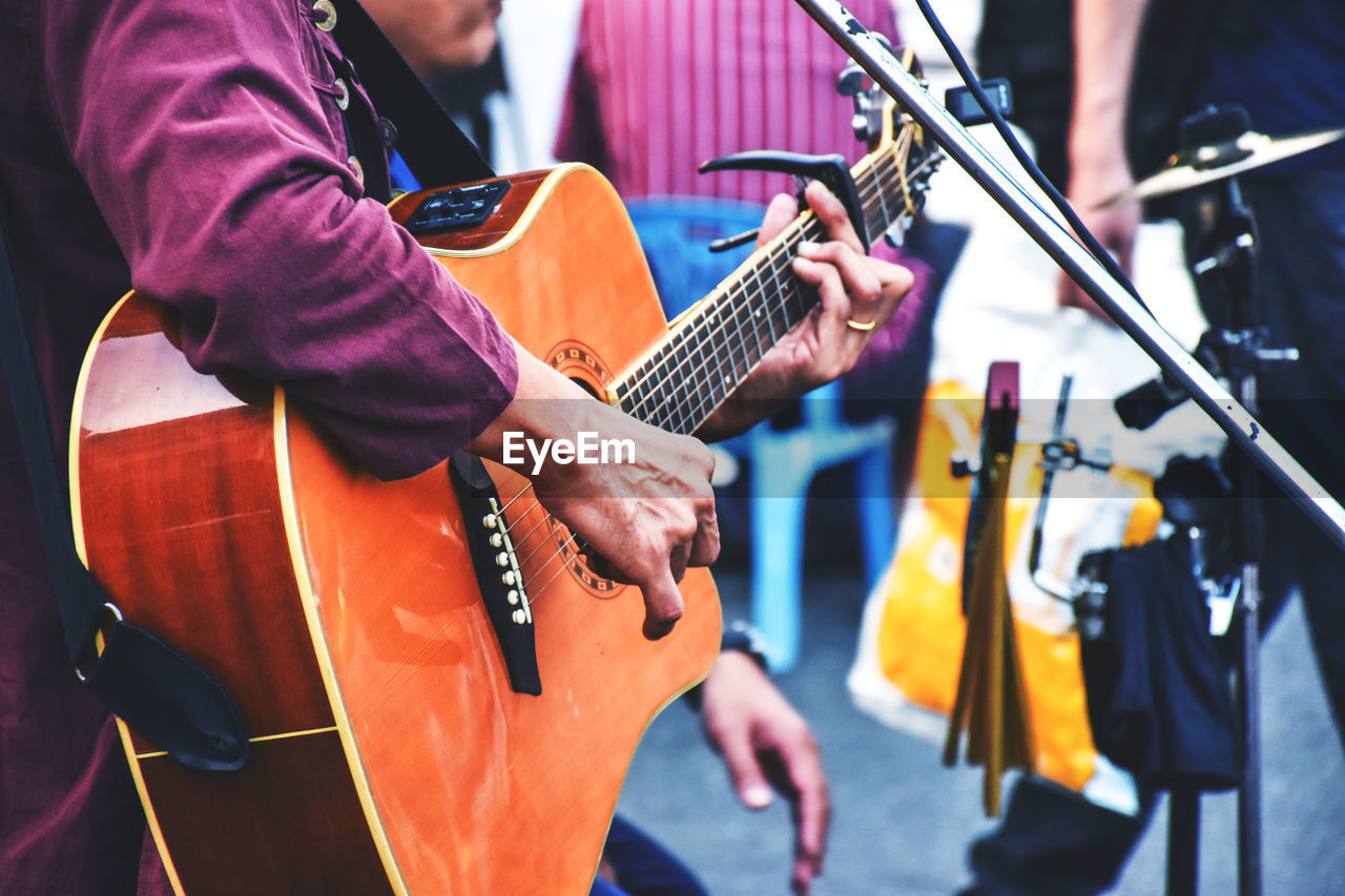 Cropped image of artist playing guitar at music concert