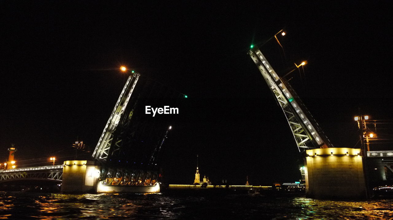 SUSPENSION BRIDGE OVER RIVER AT NIGHT