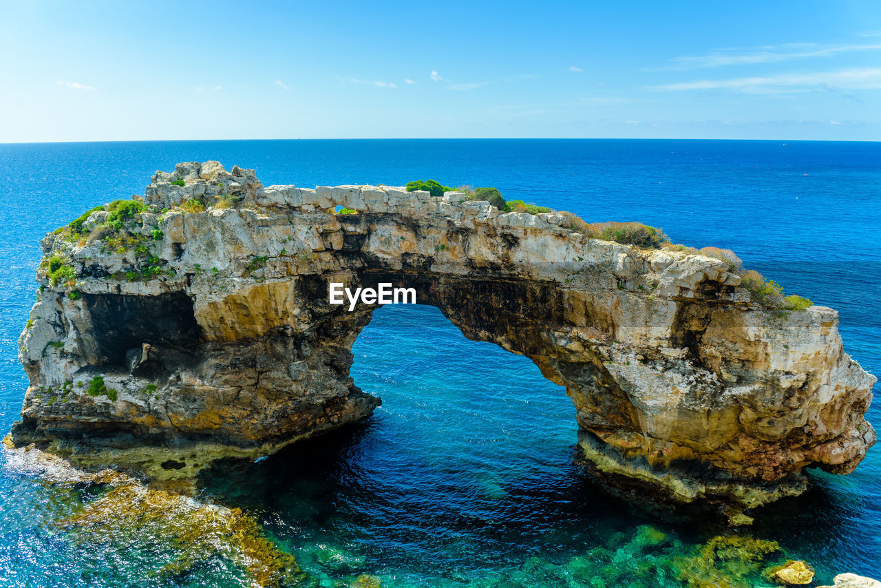 Rock formation in sea against blue sky