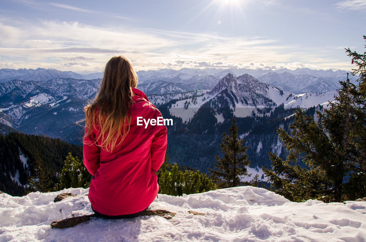 Women with long blond hair looking over panoramic snowcapped mountain view