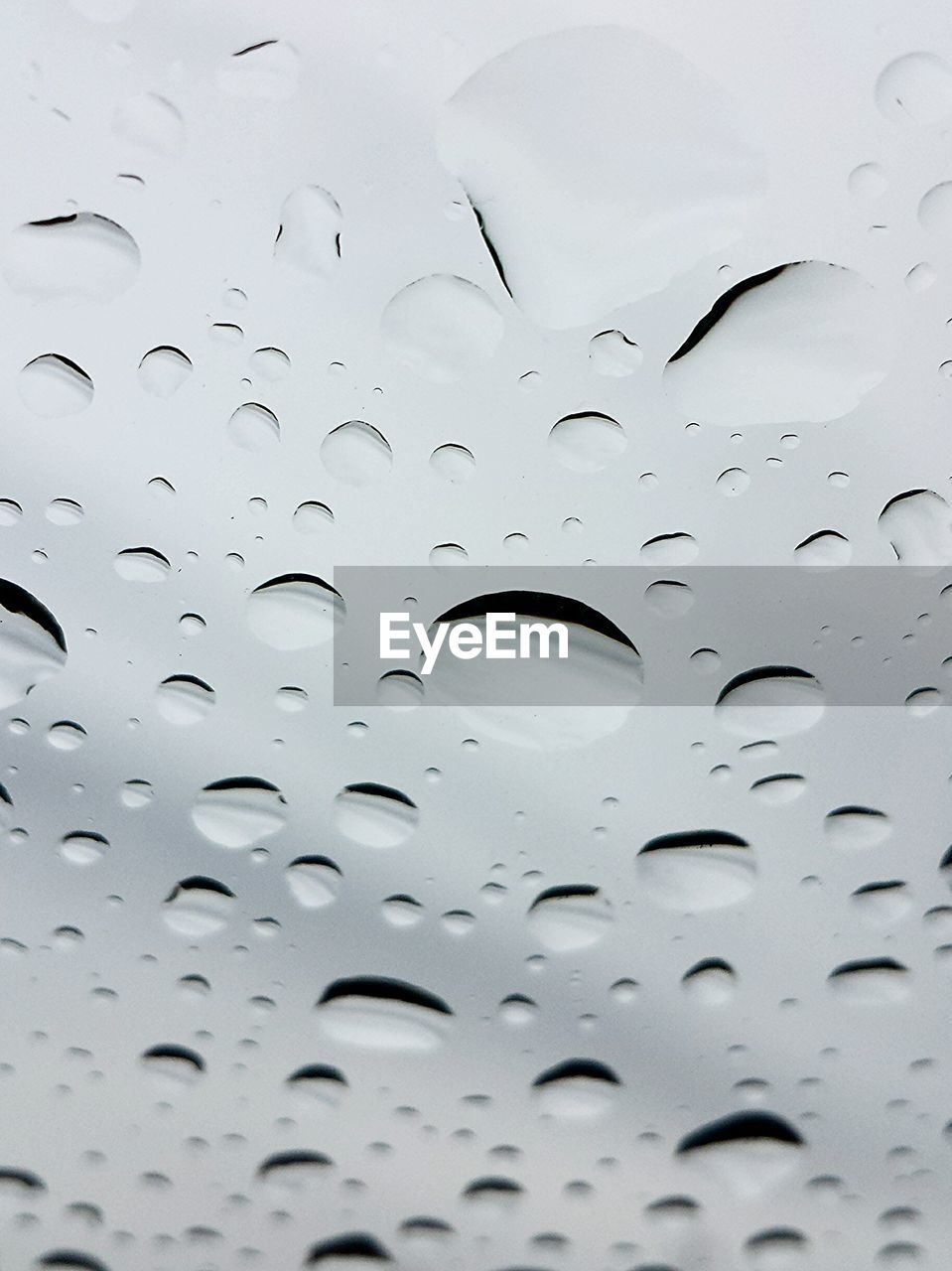 Close-up of waterdrops on glass against the sky