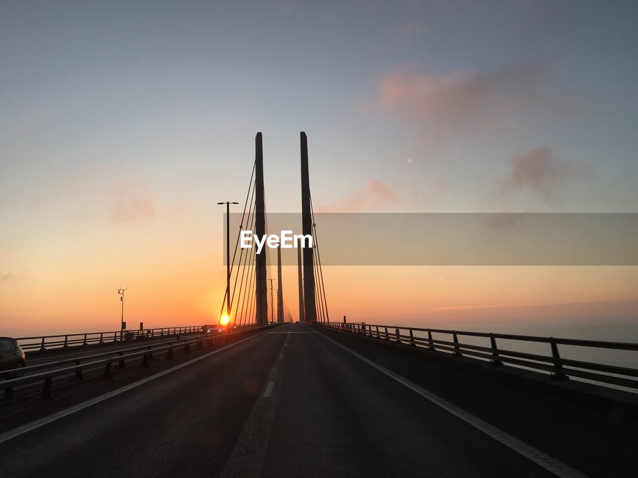 Scenic view of road along sea against cloudy sky