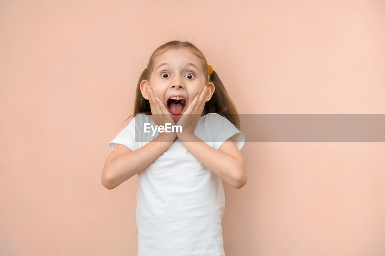 portrait of cute girl with eyes closed standing against pink background