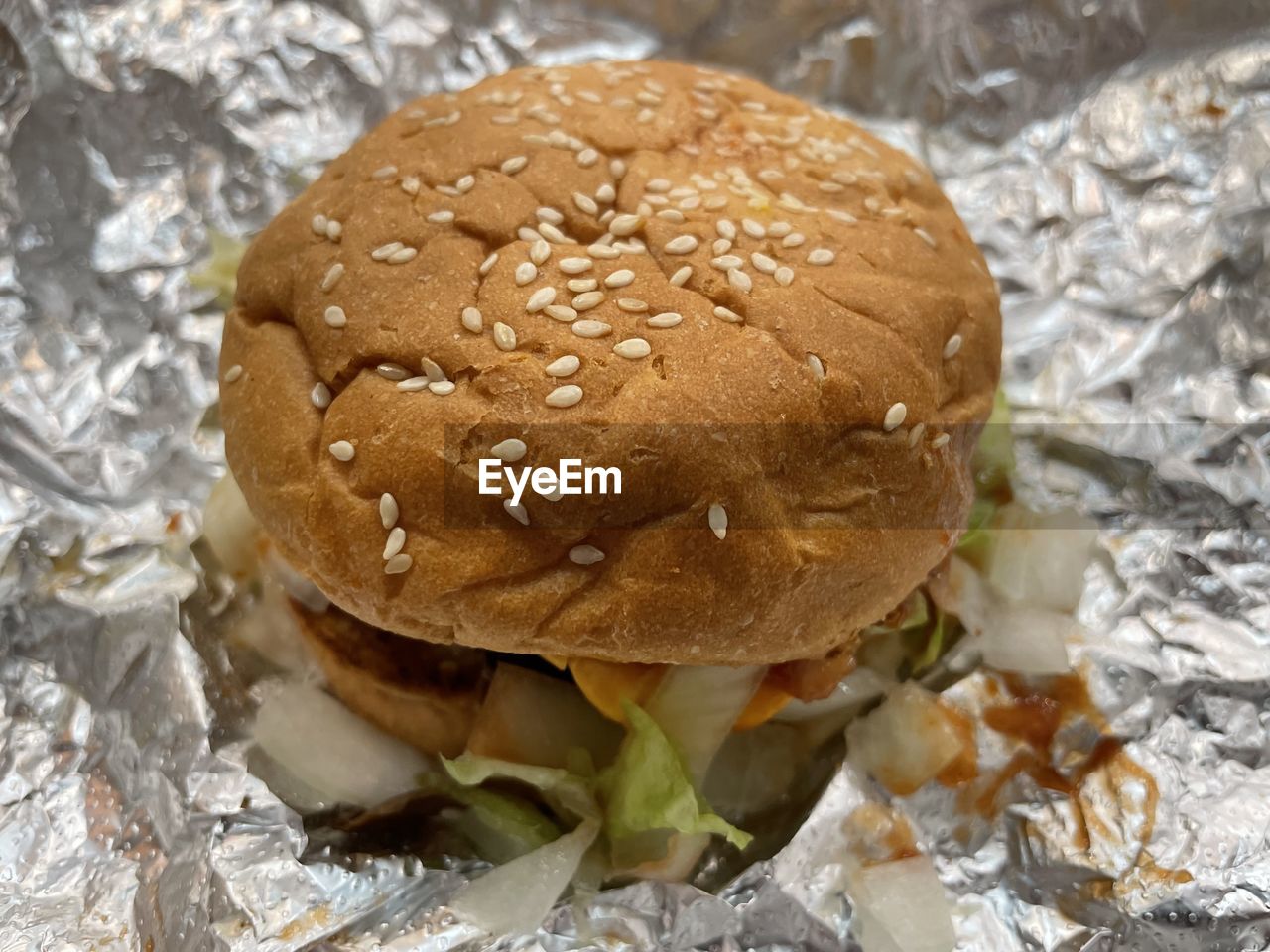 food, food and drink, fast food, freshness, unhealthy eating, hamburger, dish, bread, no people, sandwich, close-up, bun, meal, high angle view, indoors, paper, still life, seed, produce, brown