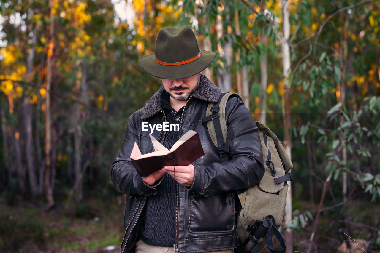 MAN HOLDING HAT WHILE STANDING ON LAND