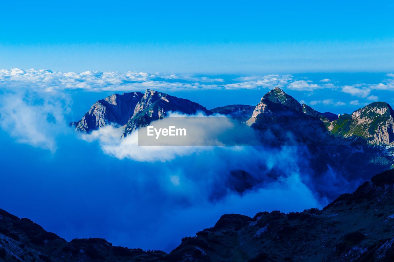 Scenic view of snowcapped mountains against blue sky