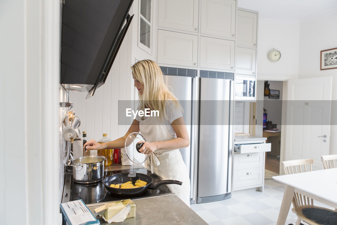 Teenage girl cooking food in kitchen at home