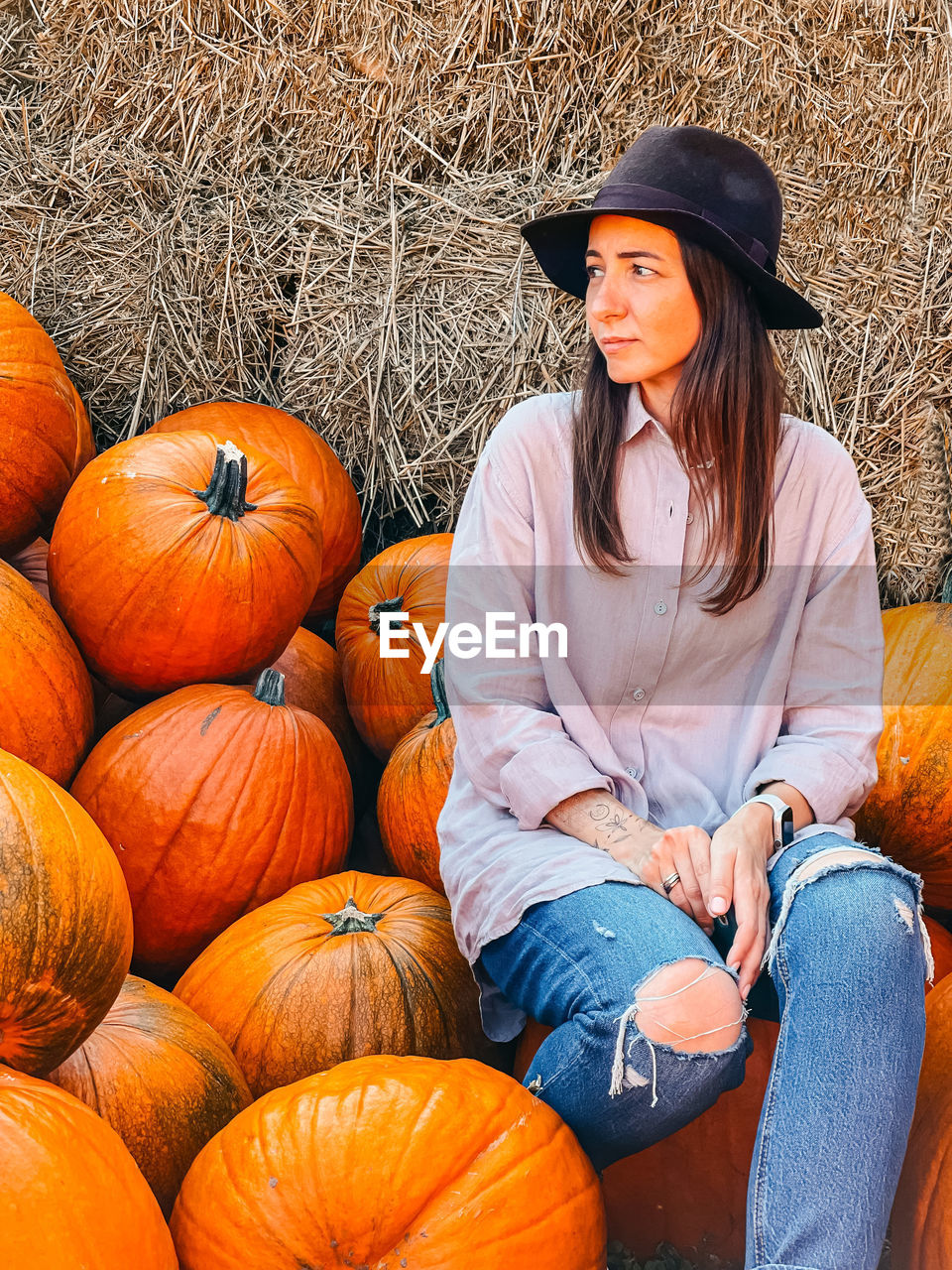 FULL LENGTH OF SMILING BOY SITTING ON PUMPKIN