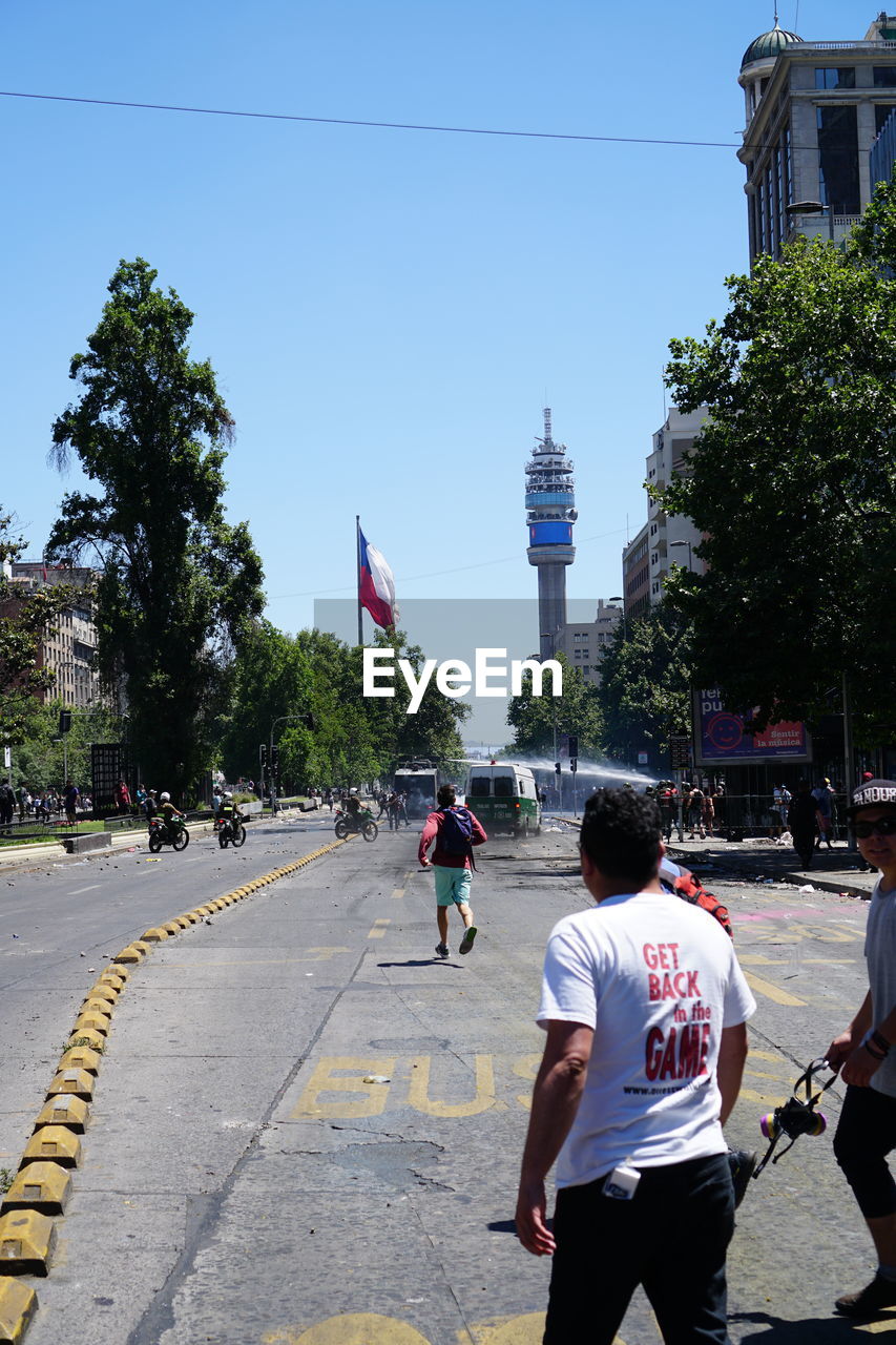 People walking in city against clear sky