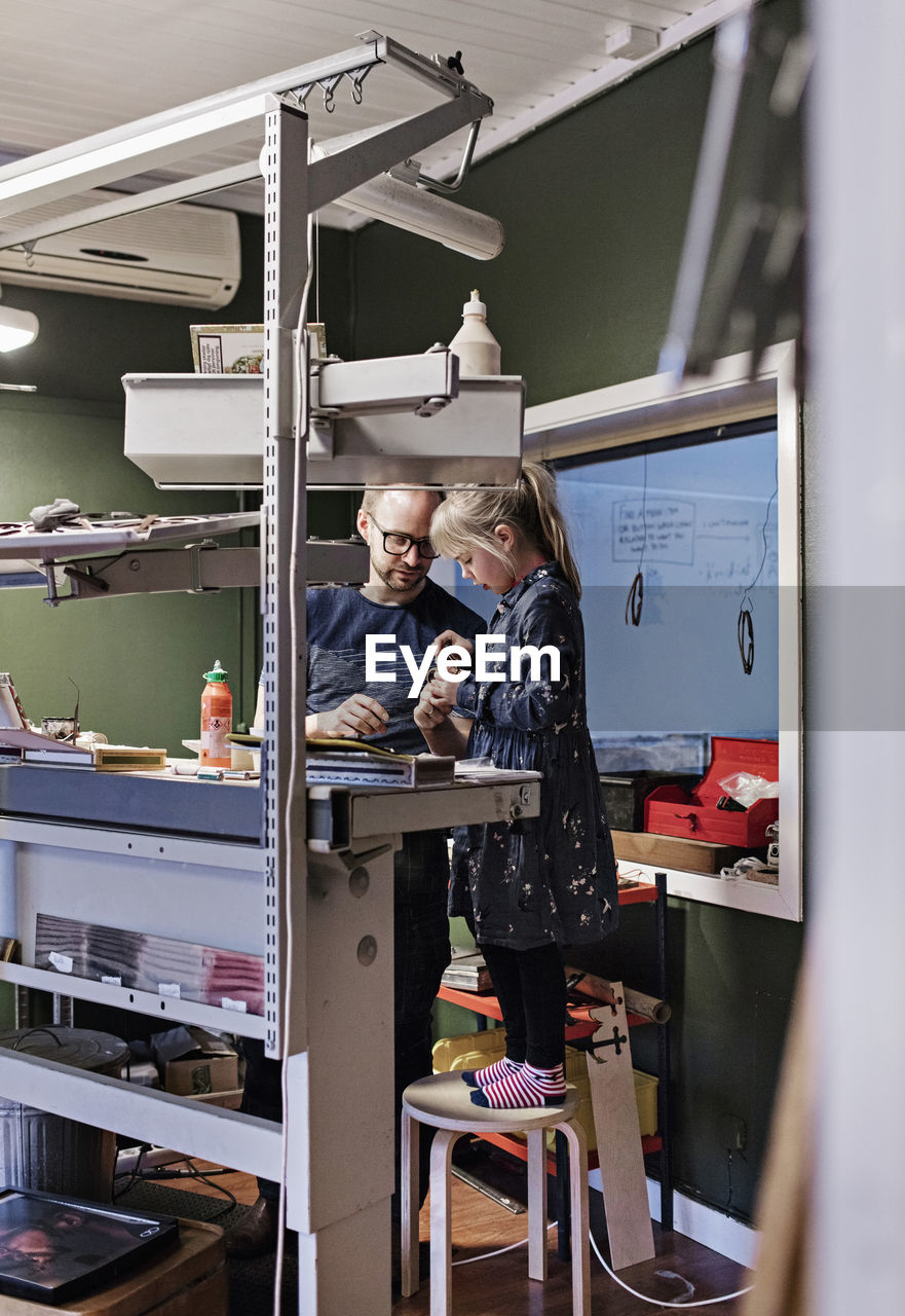 Father and daughter making eyeglasses at workshop