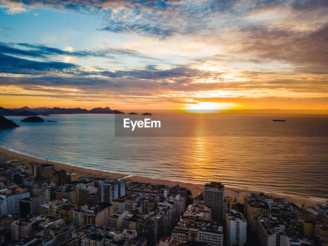 Scenic view of sea by buildings against sky during sunset